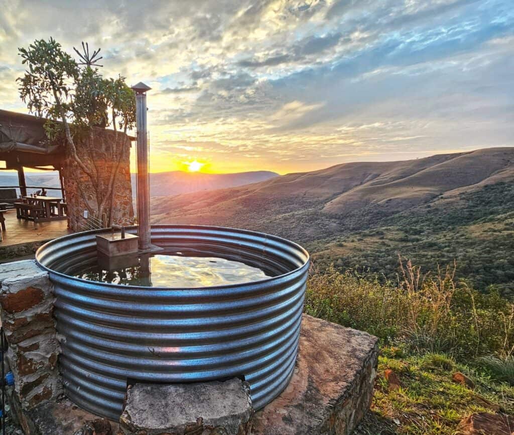 Wolwekrans hot tub overlooking sunset over rolling hills.